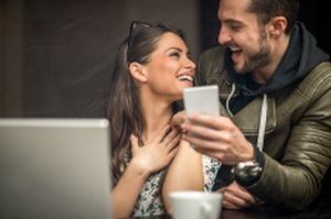 stock-photo-61264968-laughing-couple-in-coffee-shop-looking-at-mobile-device
